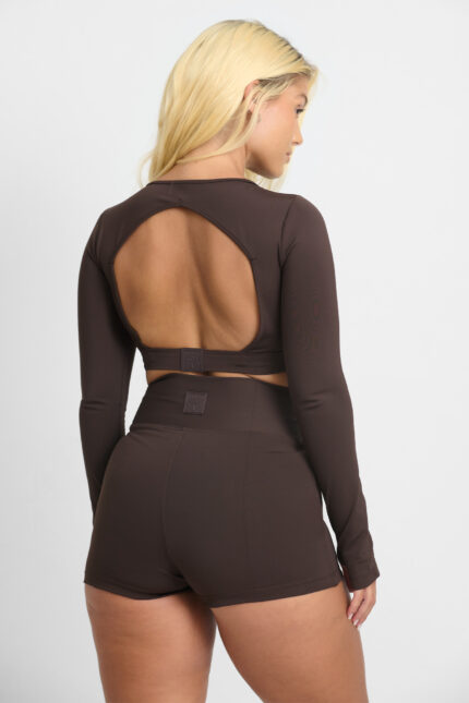 Mulher de costas usando SHORT YANI CACAU marrom, top cropped de manga longa com recorte nas costas.